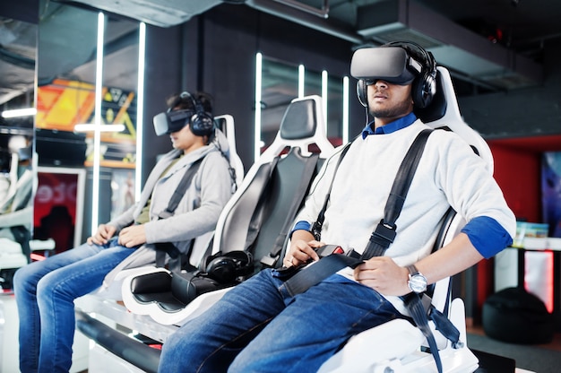 Two young indian people having fun with a new technology of a vr headset at virtual reality simulator