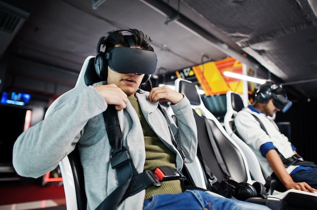 Photo two young indian people having fun with a new technology of a vr headset at virtual reality simulator