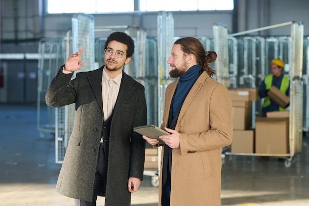 Два молодых межкультурных бизнесмена в формальной одежде обсуждают место для офиса