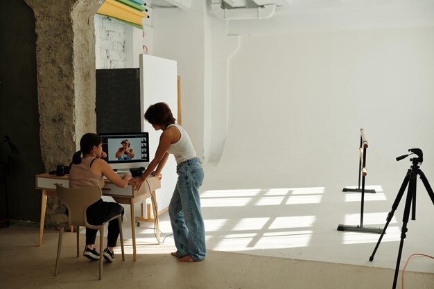 Photo two young intercultural women discussing new shots on computer screen