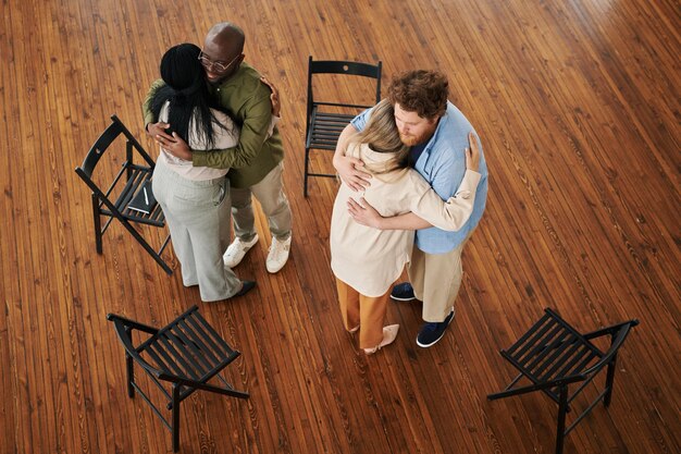 Two young interracial couples standing in embrace while comforting each other