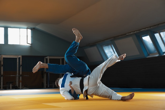 Two young judo fighters in kimono training martial arts in the gym with expression in action and motion