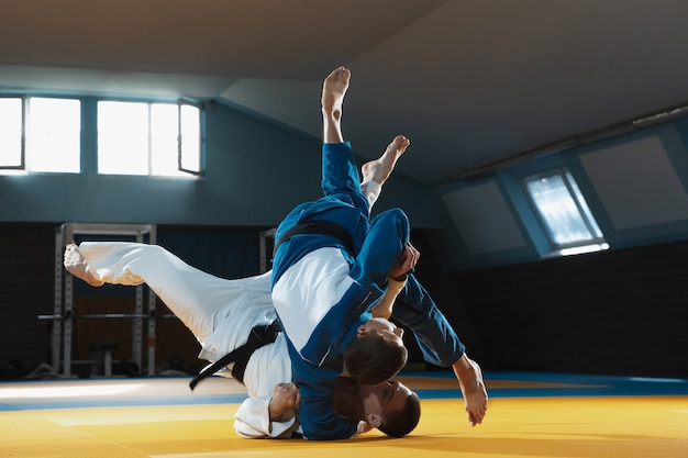 Two young judo fighters in kimono training martial arts in the gym