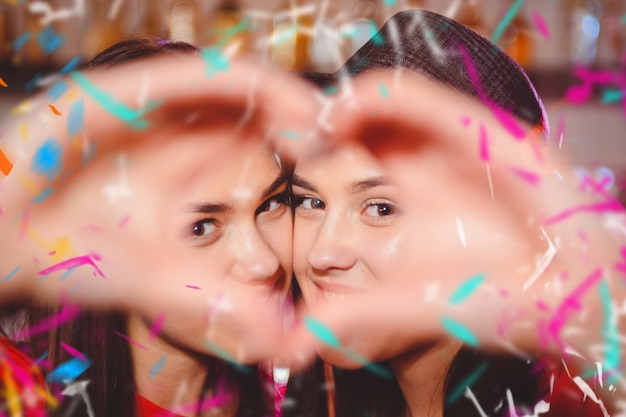 Two young lesbian girls make a heart with their hands