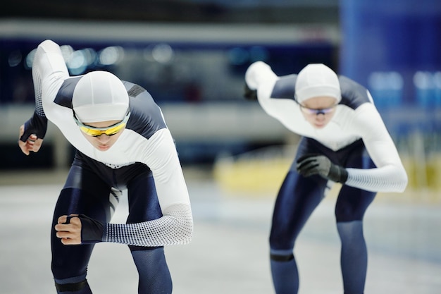 Two young male figure skaters in sports uniform moving forwards