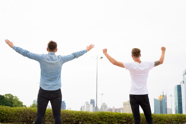 Two young man with arms raised outdoors