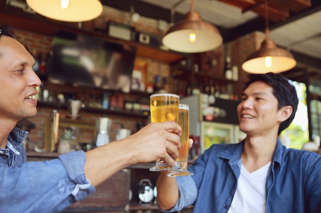 Двое молодых людей сталкиваются с двумя стаканами пива, чтобы отпраздновать их успех.