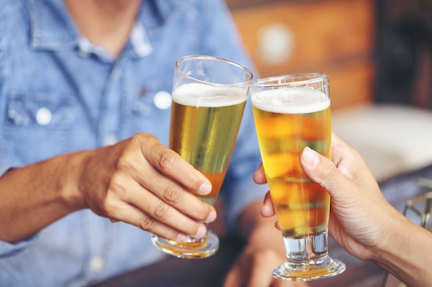 Due giovani si scontrano con due bicchieri di birra per celebrare il loro successo.