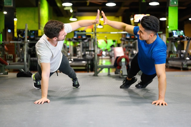 Two young men doing high planks in gym.