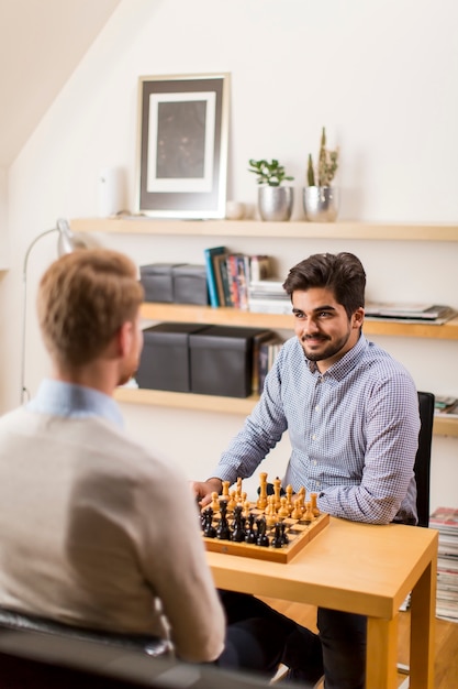 Two young men playing chess in room