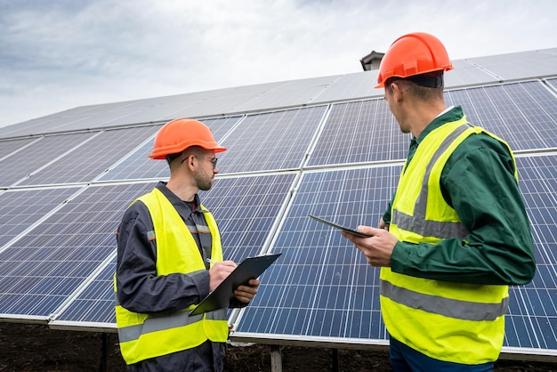 Two young men in special helmets make notes after inspecting the solar panels