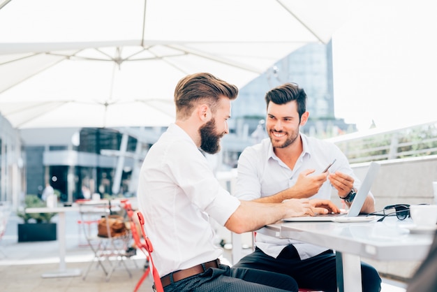 Two young modern businessman using devices