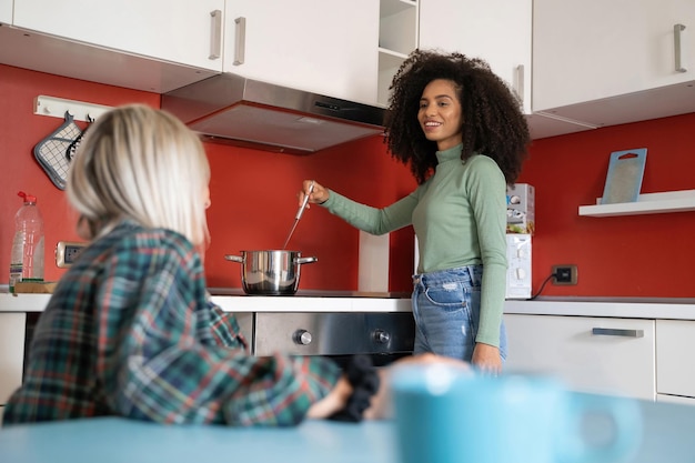 two young multiracial students girls cooking in the youth hostel kitchen talking together