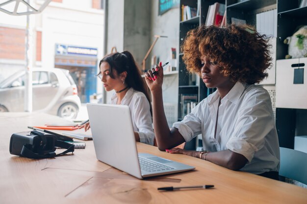 Two young multiracial women working on a project in a coworking office