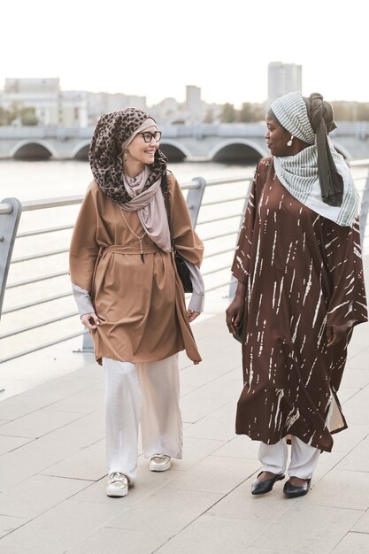 Two young muslim women talking to each other while walking in the city