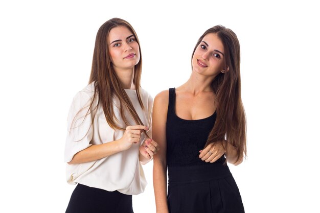 Two young nice women in white and black shirts standing on white background in studio