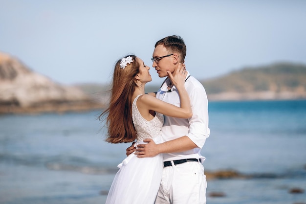 Two young people in love looking at each other with affection and understanding. Man holding his hands at the womanÃ¢ÂÂs waist. Wedding day of two lovers on the seashore. Wedding concept