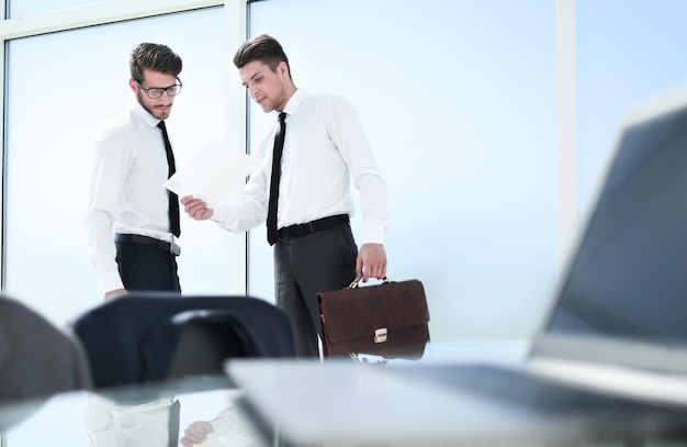 Two young people in the office are standing by the window