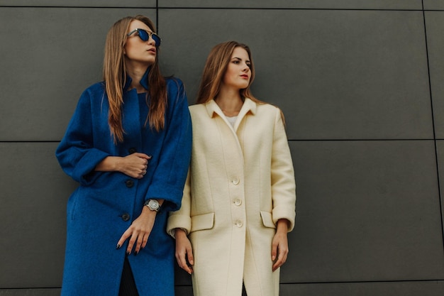 Two young pretty girls wearing coats walking together at the autumn