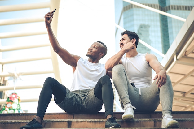 Two young runners sat to rest and took a selfie with a smile on the stairs.