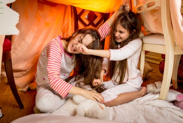 Two young sisters having a fight in bedroom