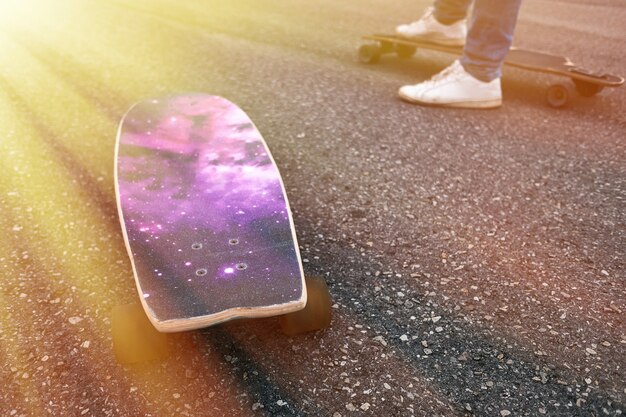 Two young skaters performing with skateboard at sunset in urban city park - Young people having fun with longboards - Extreme sport and youth lifestyle concept - Soft focus on right man foot board