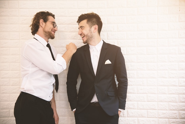 Two young smart businessmen talking together during leisure time at indoor