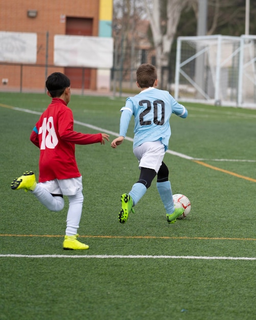 Two young soccer players kicking soccer ball on grass pitch Youth sports competition