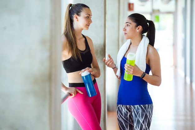 Two young sporty woman stretching their bodies in gym.