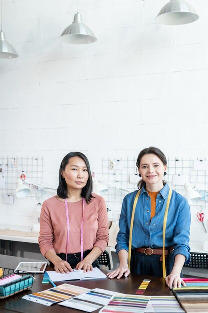 Two young successful businesswomen working over fashion collection in workshop