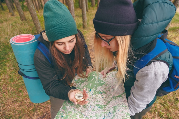 Two young tourist determine the route map and compass