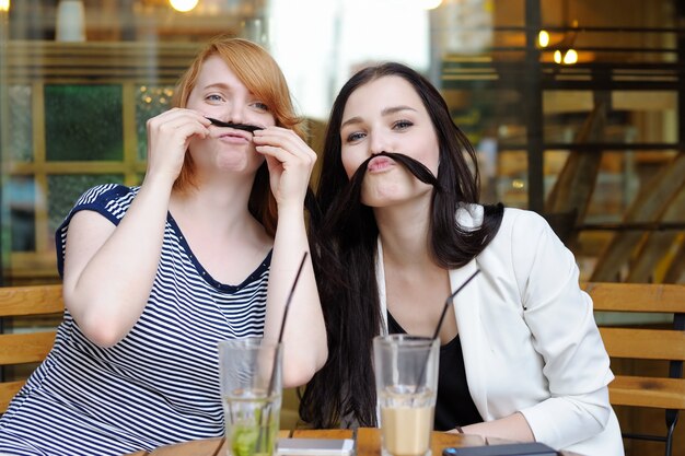 Two young woman having fun at the outdoors cafe