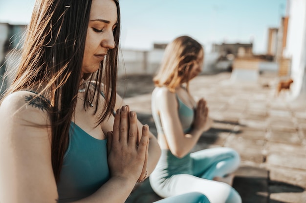 Two young woman practicing yoga on a rooftop terrace.