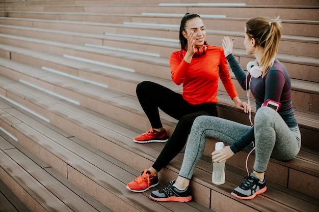 Two young woman resting on stairs after running