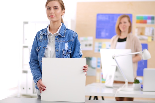 Two young woman standing near desk with instruments plan and laptop