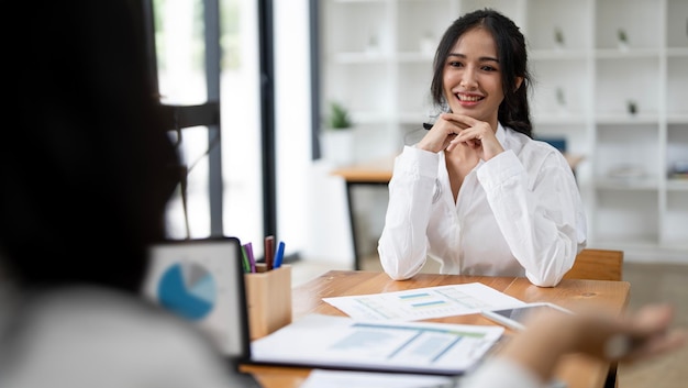 Two young woman talking and discussing together sitting at office