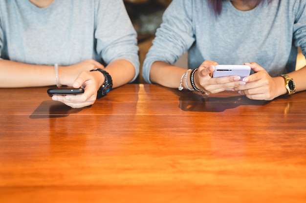 Two young woman using mobile smart phone connect online social and internet surfing