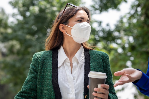 Two young women are walking down the street wearing face masks talking happily after shopping