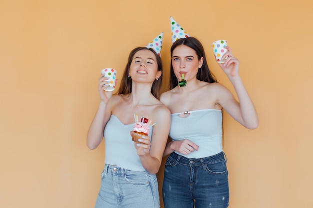 Two young women in birthday hats celebrating birthday