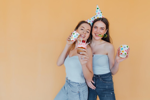 Two young women in birthday hats celebrating birthday