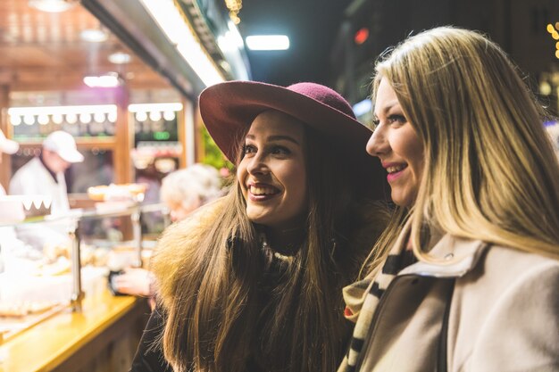 Due giovani donne che comprano cibo al mercatino di natale a monaco di baviera