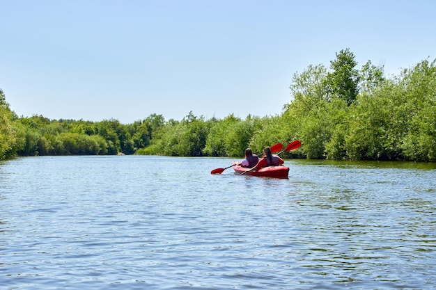 Two young women canoe on calm river Kayaking and outdoor activities on weekend