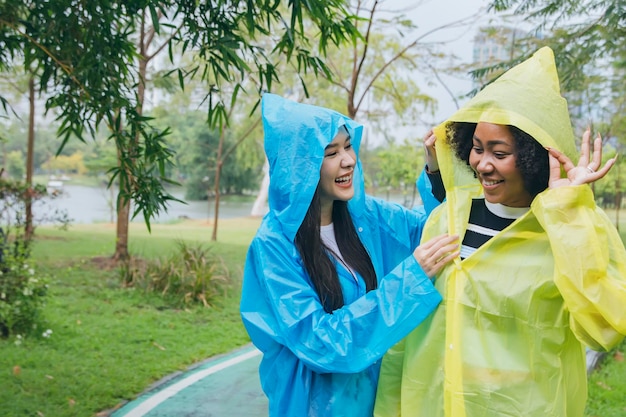 Two young women different nationalities and cultures enjoy playing in the rain in the garden