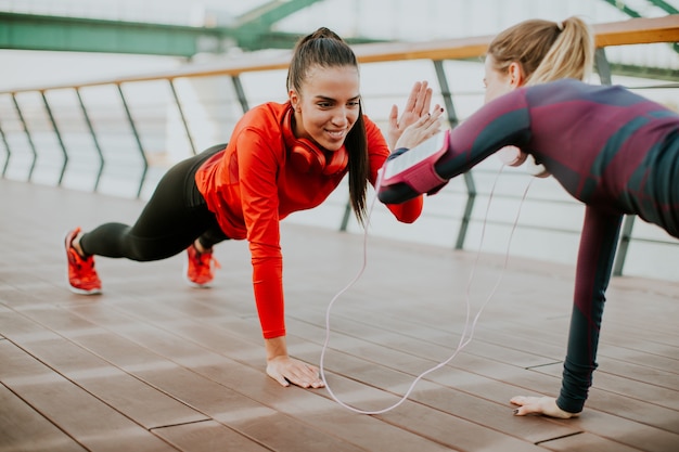 Two young women doing plank on riverside after running