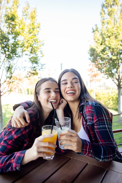 Two young women drinking juice and lemonade in the park