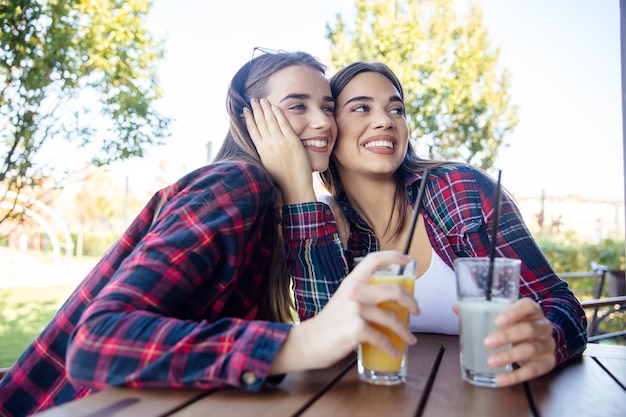 Due giovani donne che bevono succo e limonata nel parco