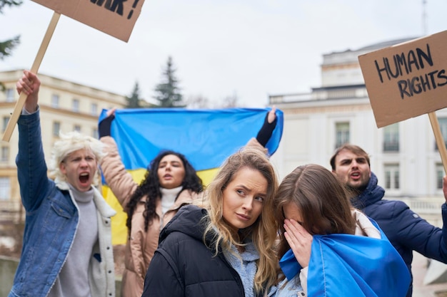 Фото Две молодые женщины обнимаются перед группой людей, демонстрирующих против войны в украине