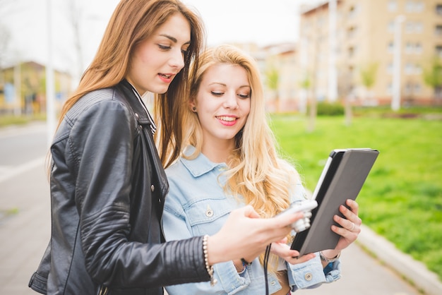 two young women friends using devices