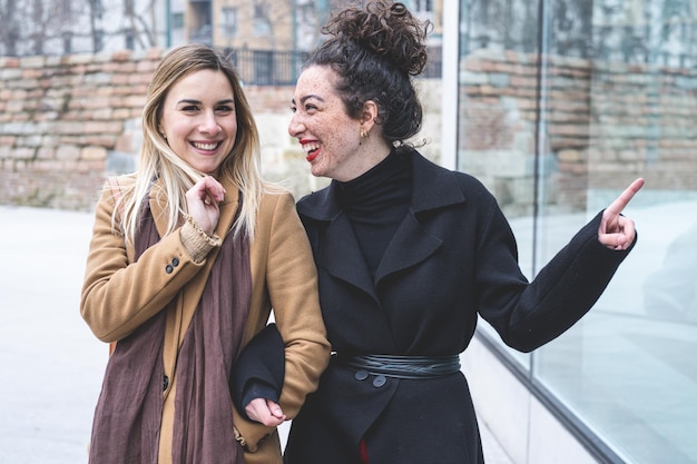 Two young women of Generation Z walking and looking something for shopping happy people smiling and laughing whlie walking outside