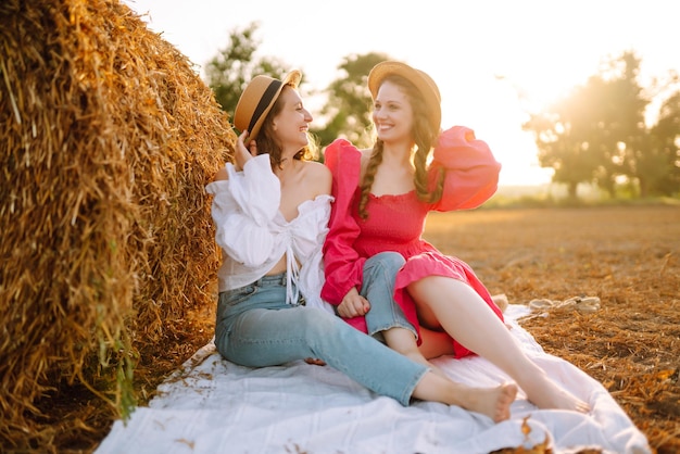 Two young women having fun near haystack Fashion concept Summer concept